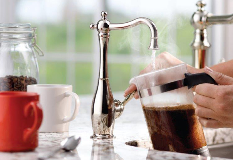 Water spout in kitchen pouring water into coffee maker