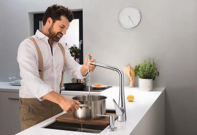 Man getting water from kitchen sink into pot for cooking